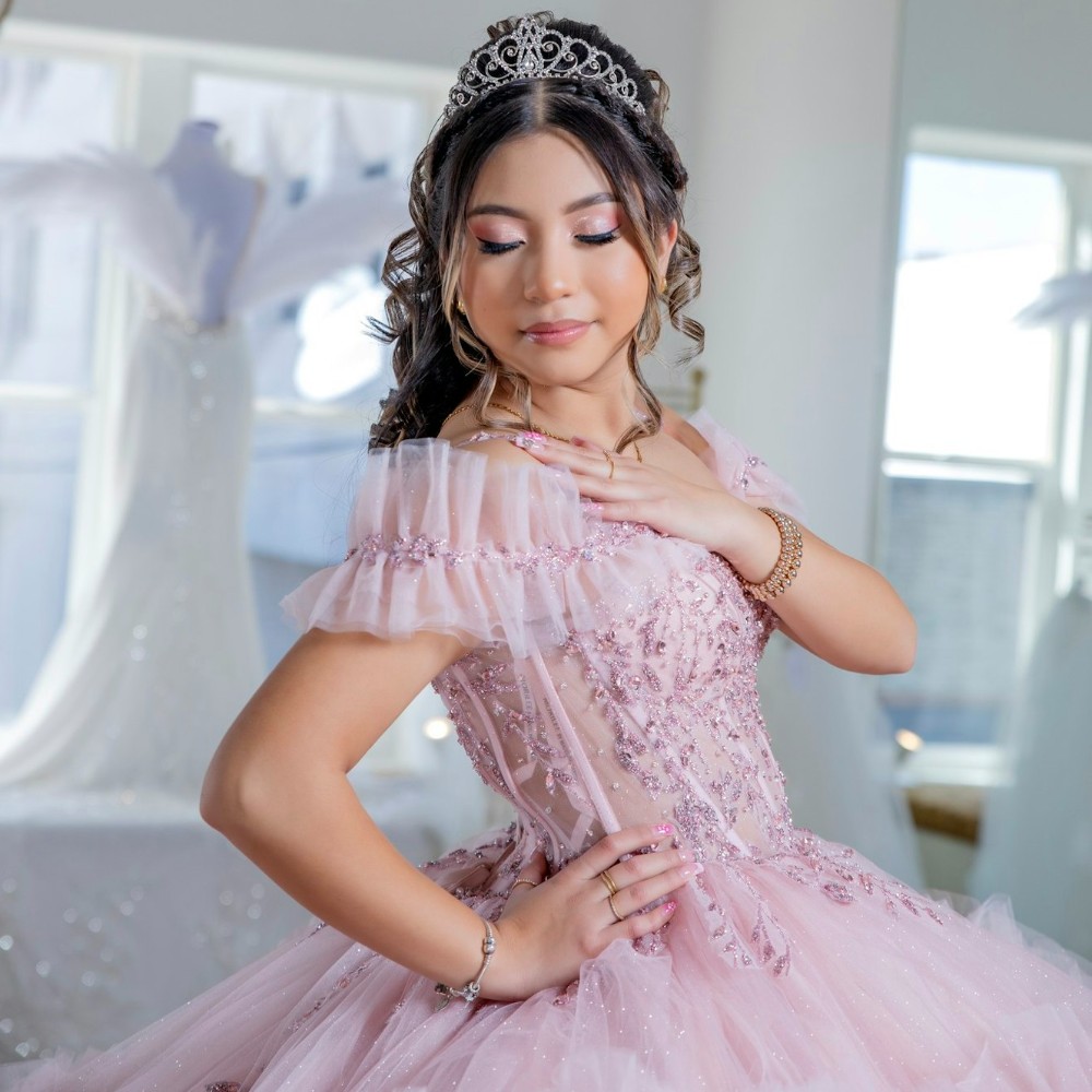 girl wearing a ruffled pink quinceanera dress looking over shoulder