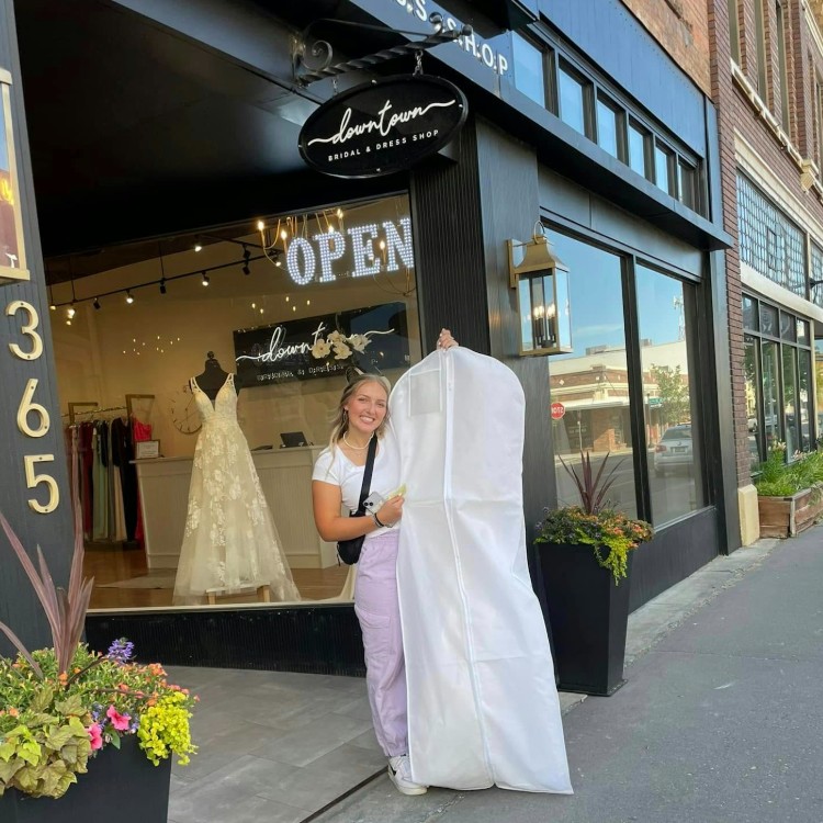 woman holding a garment bag with a wedding dress