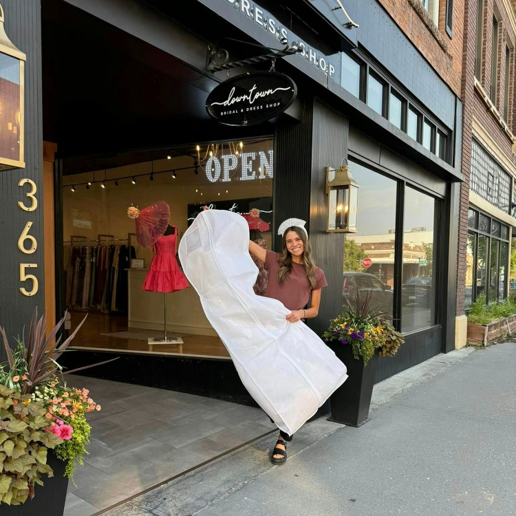 woman holding a garment bag with a wedding dress