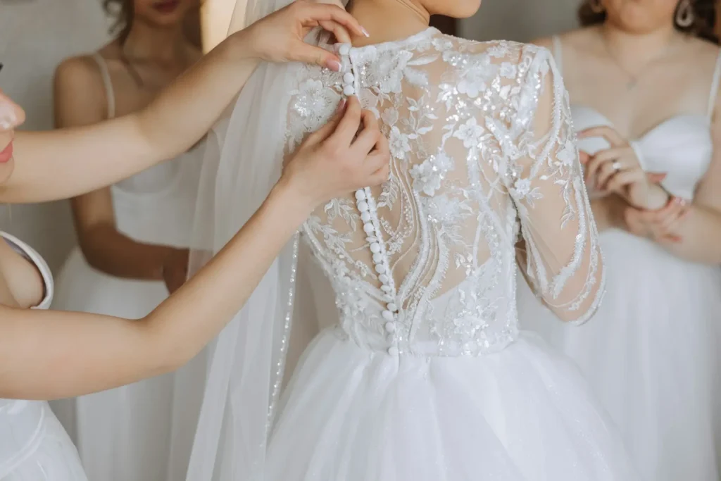 Bride getting buttons fastened on lace wedding gown during custom fitting at Downtown Bridal & Dress Shop in Idaho Falls